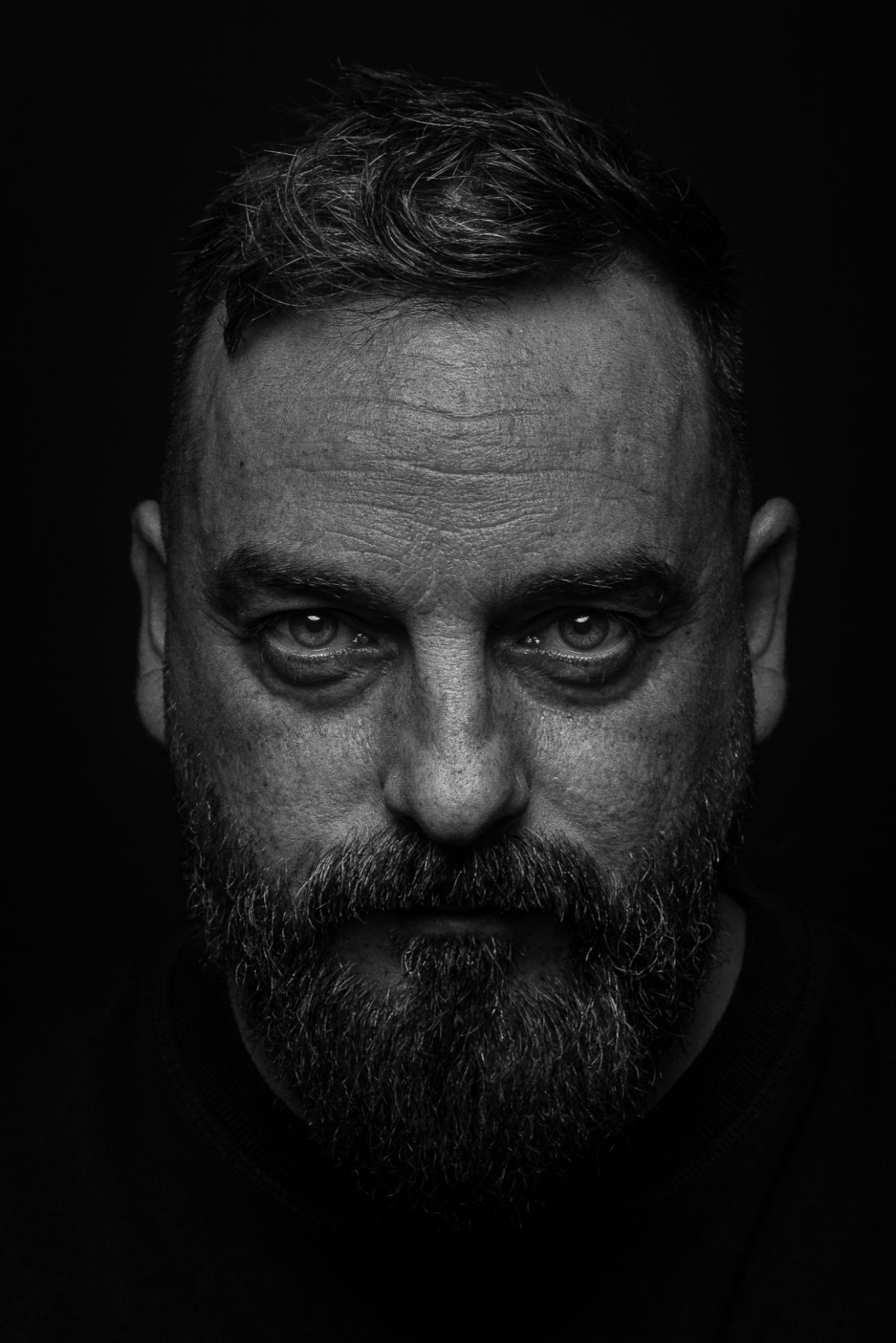 Hombre mayor con barba gris y mirada intensa, primer plano de retrato, blanco y negro – fotografía de retrato editorial por VicmanArt