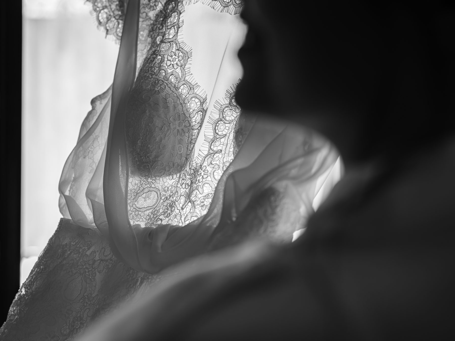 Detalle artístico de encaje de vestido de novia con silueta en contraluz, blanco y negro – fotografía de bodas por VicmanArt