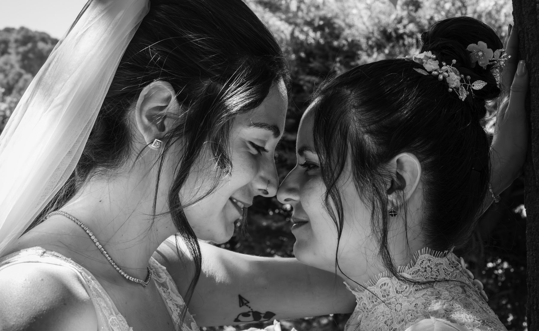 Las dos novias frente a frente con frentes juntas, retrato íntimo en exterior, blanco y negro – fotografía de bodas por VicmanArt