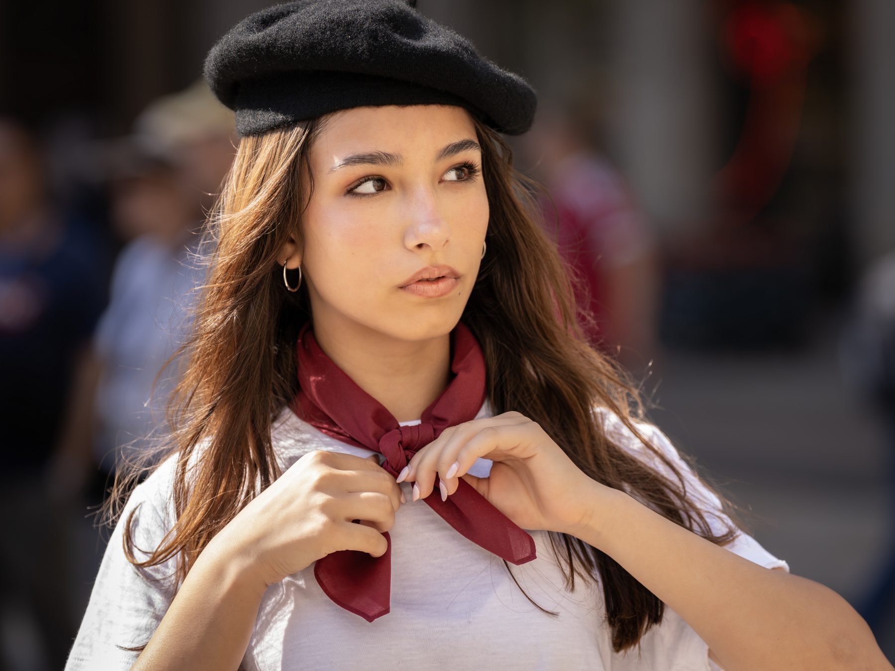 Modelo joven con boina negra ajustándose el pañuelo rojo, retrato en plaza de Barcelona – fotografía editorial de moda por VicmanArt.