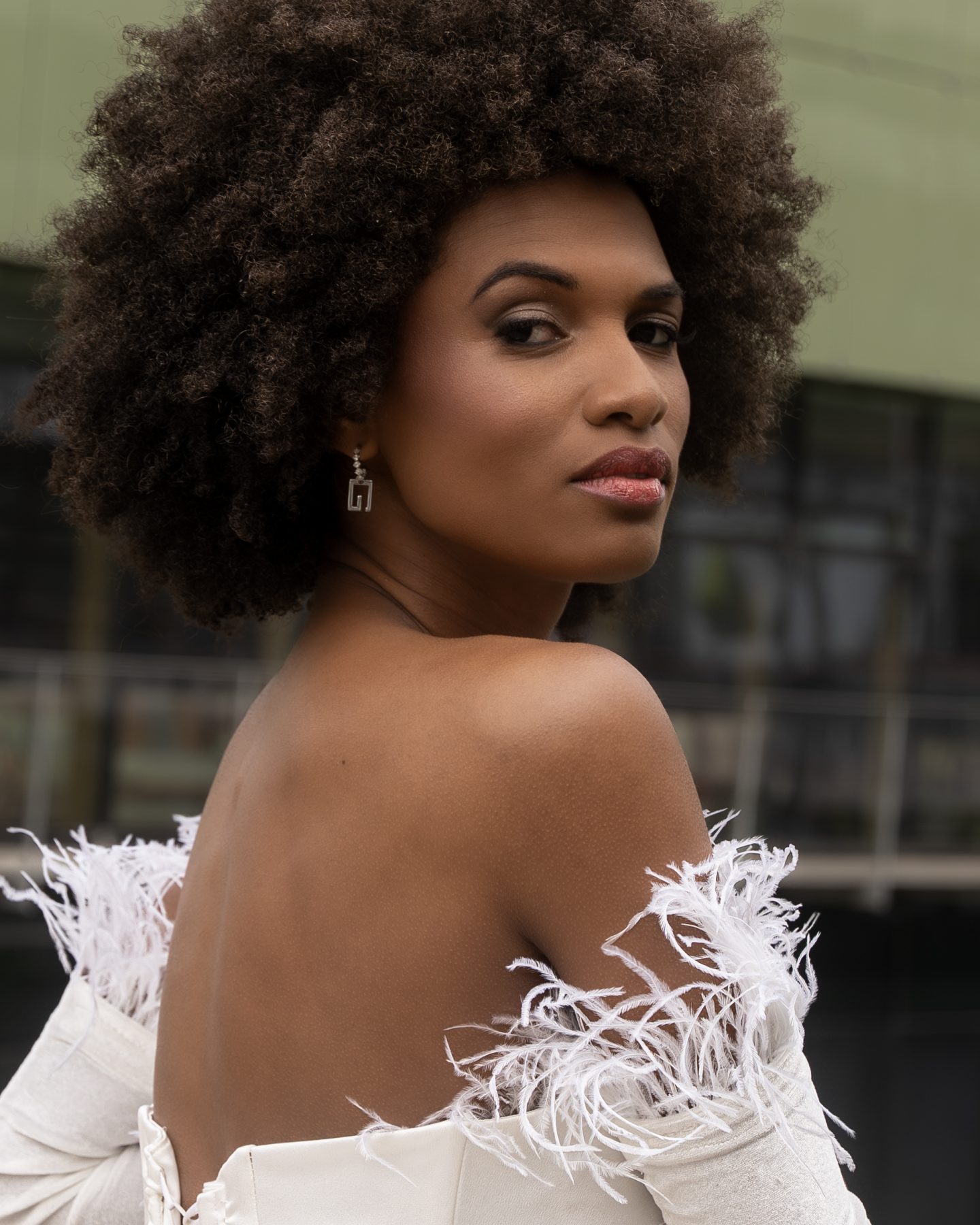 Model in a white dress with feathers looking in profile with attitude, Barcelona – editorial fashion photography by VicmanArt.