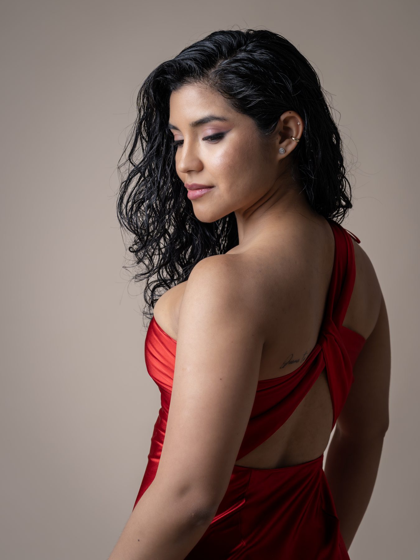 Model in a red satin dress posing, beige background – portrait photography by VicmanArt