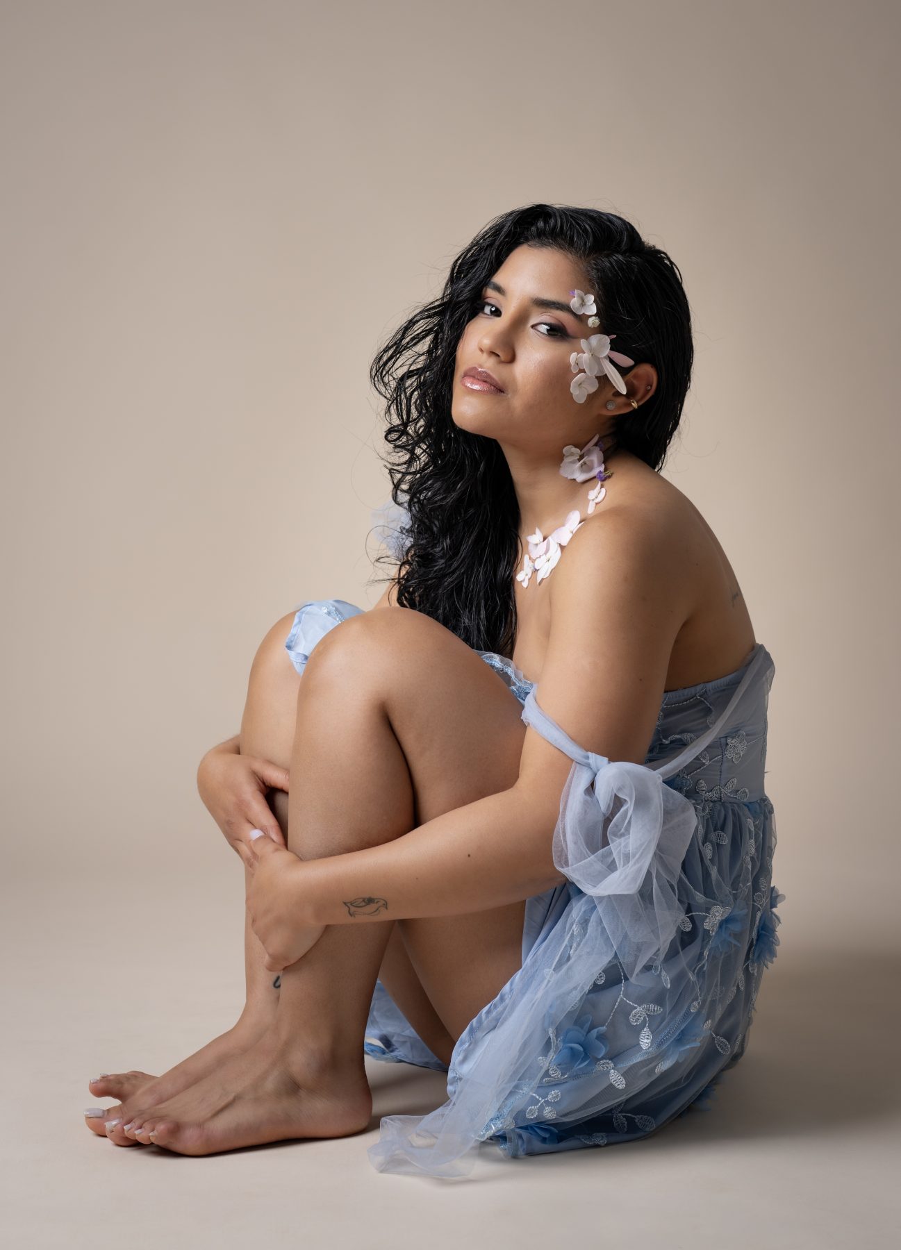 Model sitting in a blue tulle dress with hydrangea flowers in her hair, studio – portrait photography by VicmanArt