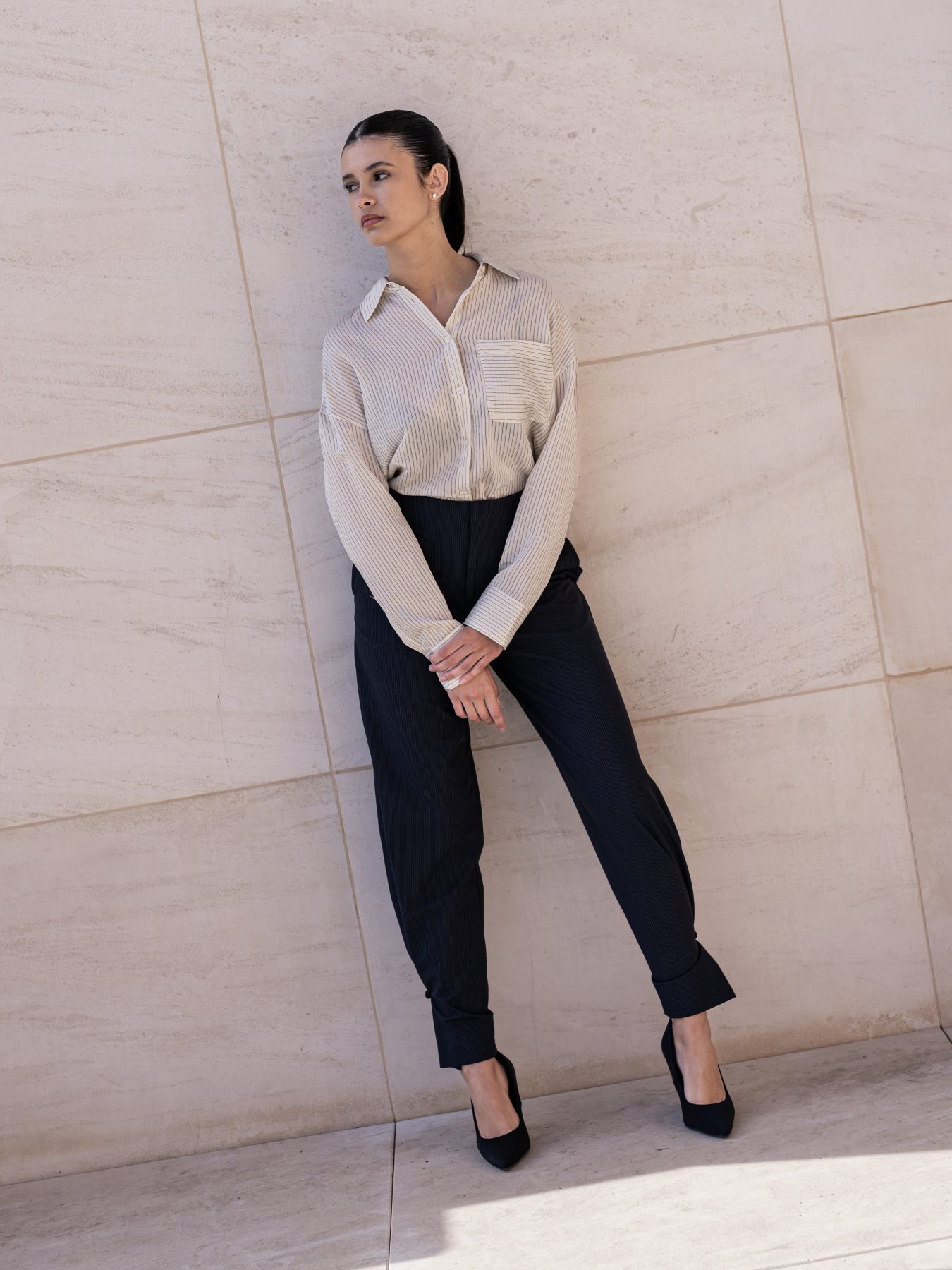 Modelo con camisa de rayas y pantalón negro de cuerpo entero apoyada en pared, Barcelona – fotografía editorial de moda por VicmanArt
