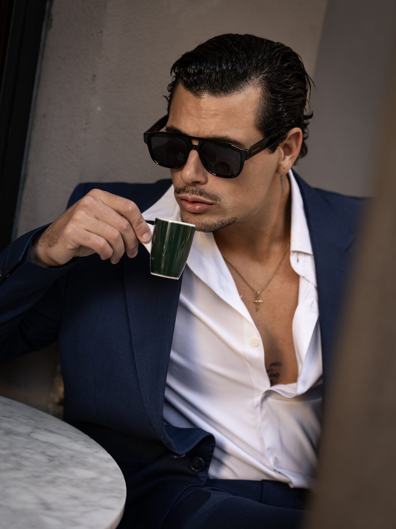 Modelo masculino con traje azul marino bebiendo café expreso en una terraza de Barcelona – fotografía editorial de moda por VicmanArt.
