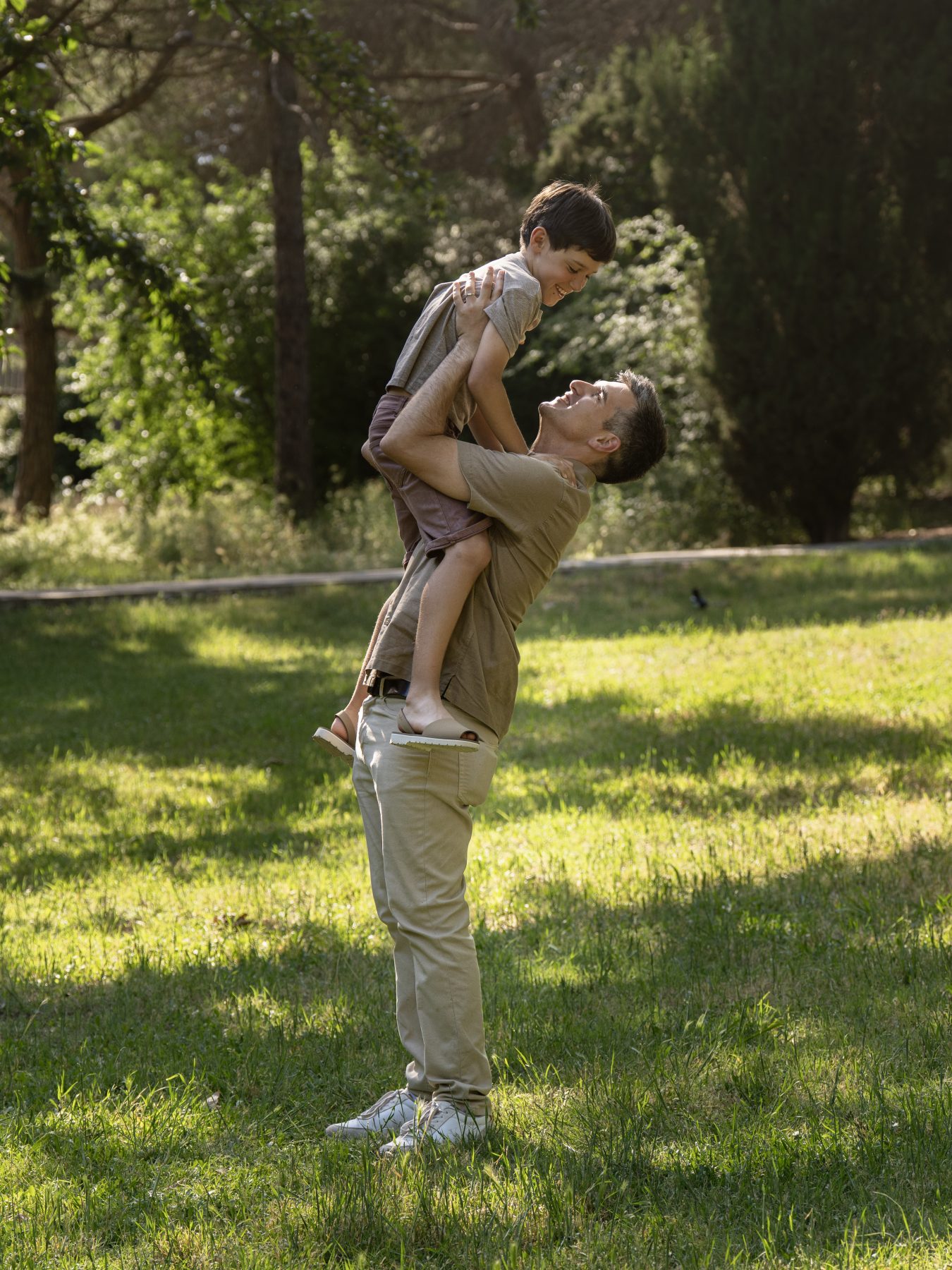 Padre lanzando a su hijo al aire entre risas en un parque de Barcelona – fotografía de familia por VicmanArt