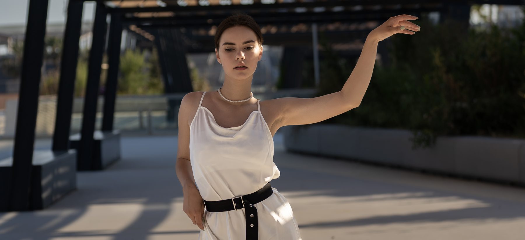 Modelo con vestido satinado blanco caminando de frente con brazo elevado en el Fòrum de Barcelona – fotografía editorial de moda por VicmanArt