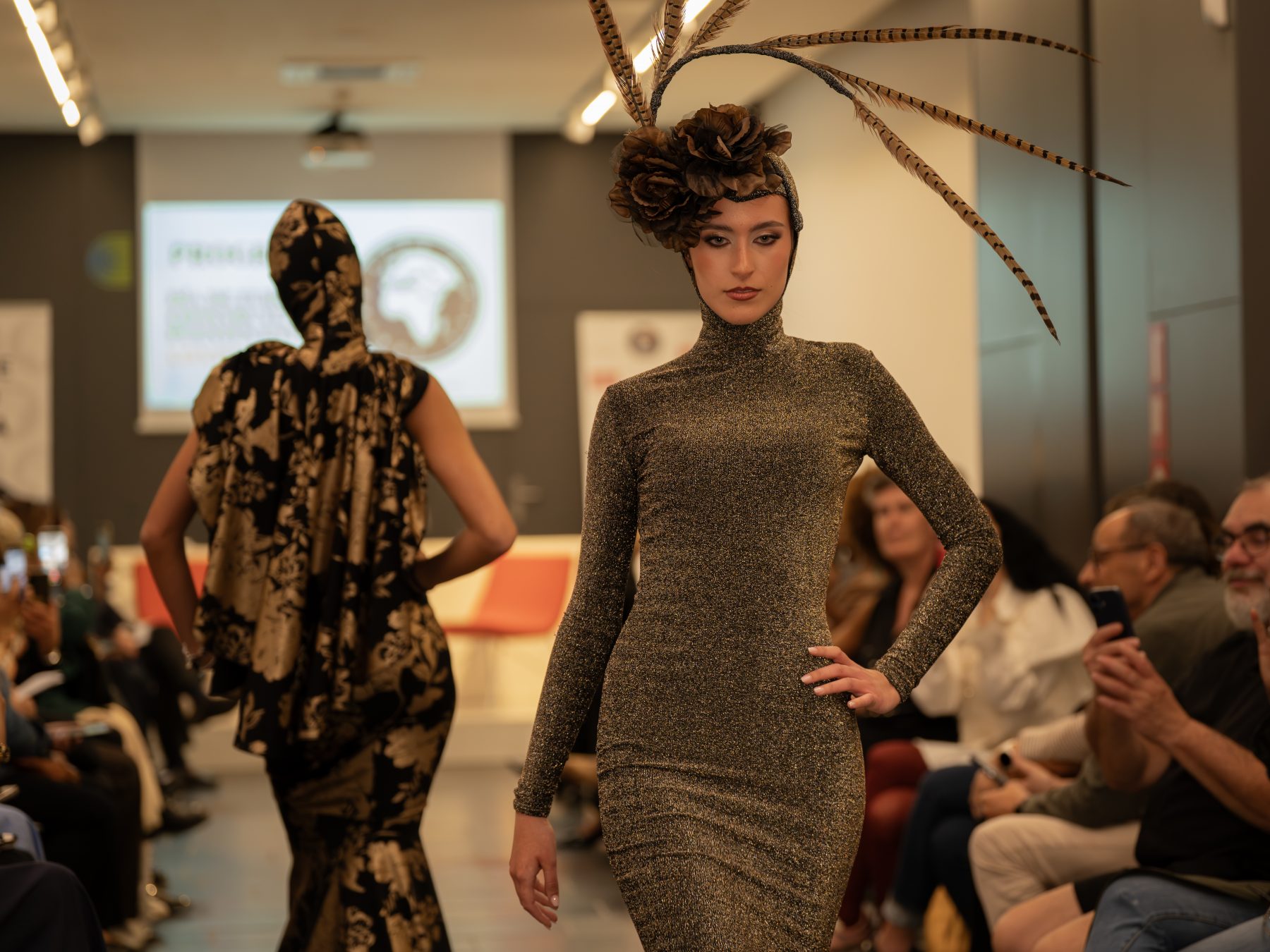 Runway model in a fitted gold dress and feather headpiece in Barcelona – fashion show photography by VicmanArt